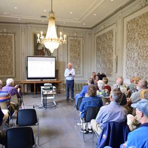 Voorzitter Hans Schouten heet iedereen welkom bij de lezing van Meindert Schroor in de trouwzaal van Crackstate
