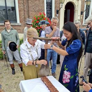 Burgemeester Avine Fokkens en wethouder Ojanne Changs snijden de speciale turfcake aan met een originele turfsteker